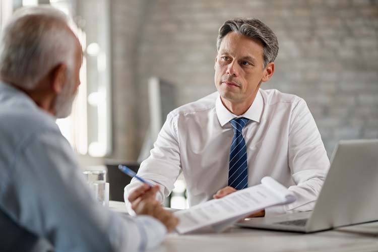 Financial advisor having a meeting with senior man and talking with him about terms of the contract in the office.